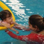 Babyschwimmen und kognitive Entwicklung Säugling beim betreuten Schwimmtraining im Wasser